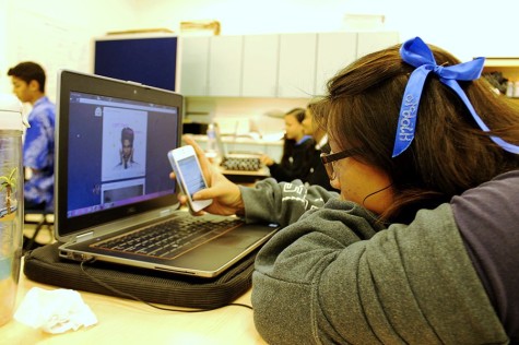 Junior Chanel Browne hides her phone behind her computer so that she can send a text. Today's teens often use more than one information device at the same time, including tablets, smartphones, game systems, and laptops. By Maile Sur.